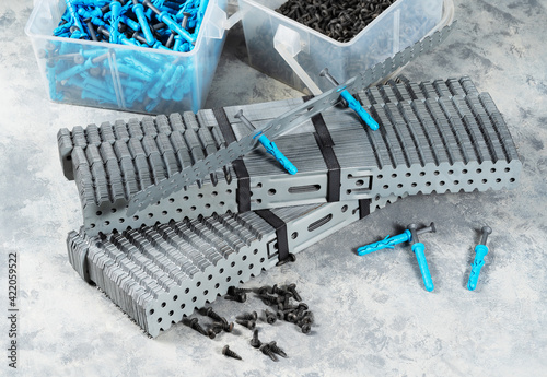 Self-tapping screws and dowels in plastic containers on a concrete table. Steel screw and plastic anchor for fixing in a concrete wall.