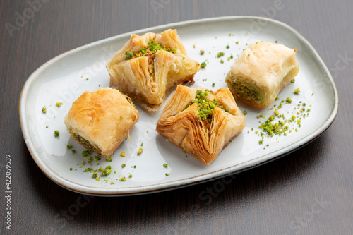 Baklava a dessert originating in the Middle East made of phyllo pastry filled with chopped nuts and soaked in honey.
