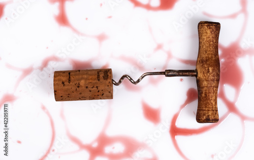 фотографія Wine cork, corkscrew and round, red wine stain on white table cloth