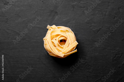 Fresh italian pasta l on a dark background with copy space for text. Tagliatelle pasta nests.