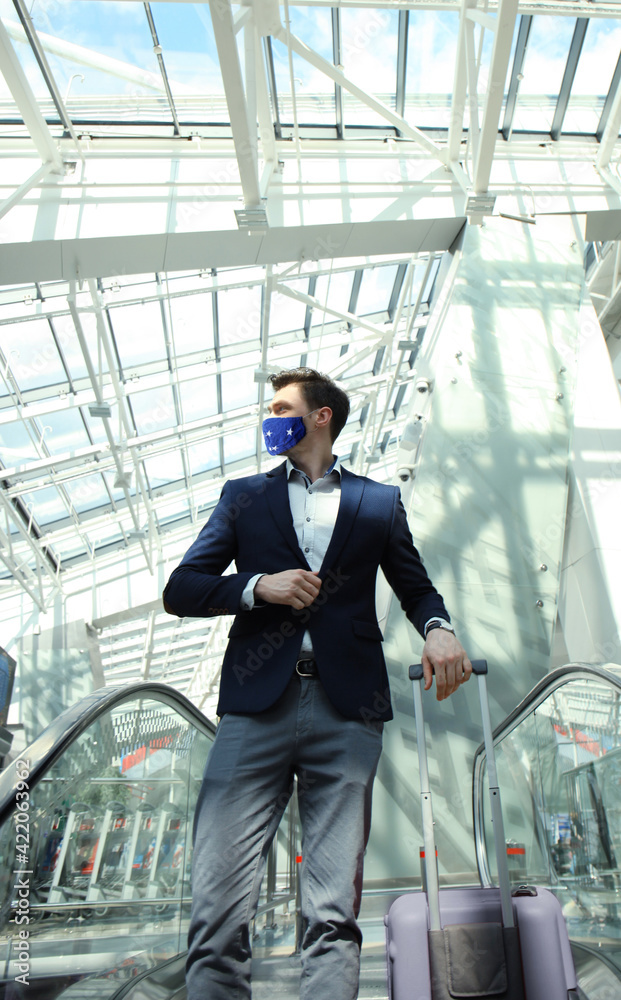 Businessman in protective mask at the airport going down the escalator. Businessman in protective mask at the airport going down the escalator.