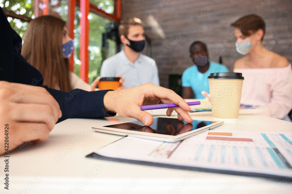 Fototapeta premium Group of young business people in preventive masks discussing something while working in the creative office