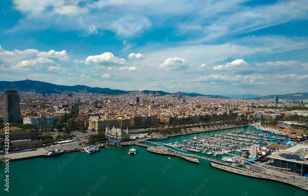 view of Barcelona, the capital of Catalonia. Flight over the famous city coastline, port and cityscape in Spain, Europe.