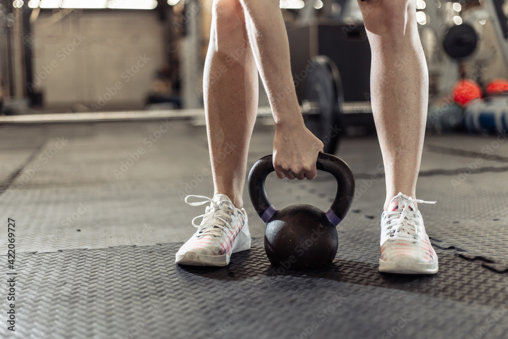Woman's hand holding a heavy kettlebell in the gym - obrazy, fototapety, plakaty 