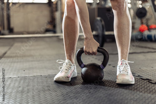 Woman's hand holding a heavy kettlebell in the gym