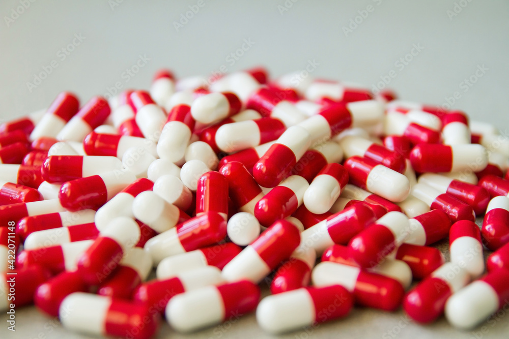 Red and white pills on the table. Medical capsules. Medicine. Pharmaceuticals. Bioactive additives. Vitamins. Illness. Disease. Tablets for health.