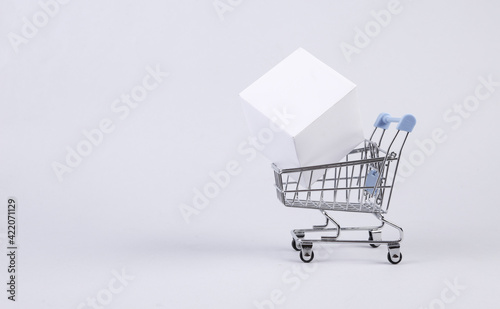 Shopping cart with white cube on white background