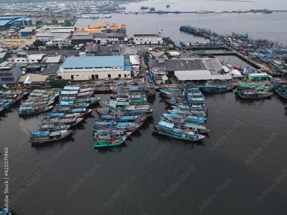 Aerial drone view of Muara Angke Beach with wooden boats leaning beside the pier. With noise cloud after rain. Jakarta, Indonesia. March 21, 2021