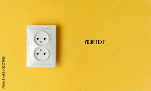 Double power socket on a yellow wall. Studio shot. Minimalism. Copy space