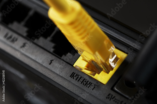 A yellow patch cord is inserted into the Wi-Fi port of the router to access the Internet. photo