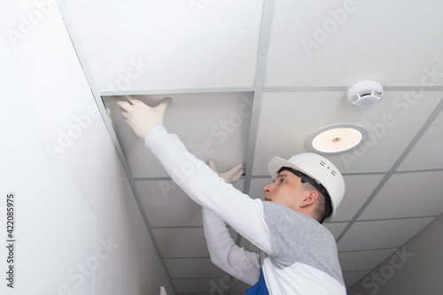 Foto master of communications maintenance, opens the suspended ceiling, for the repai