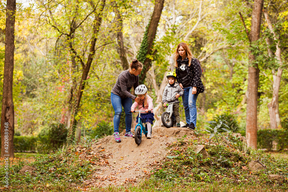 Mothers teaching and supporting their kids on bike ride