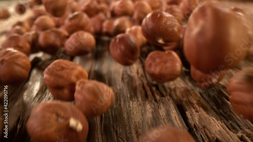 Super Slow Motion Detail Shot of Hazelnuts Rolling Towards on Wooden Background at 1000fps. photo