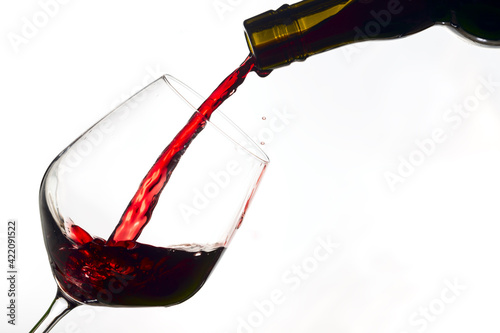 Принти на полотні red  wine poured from a bottle into wine glass on white background, isolated