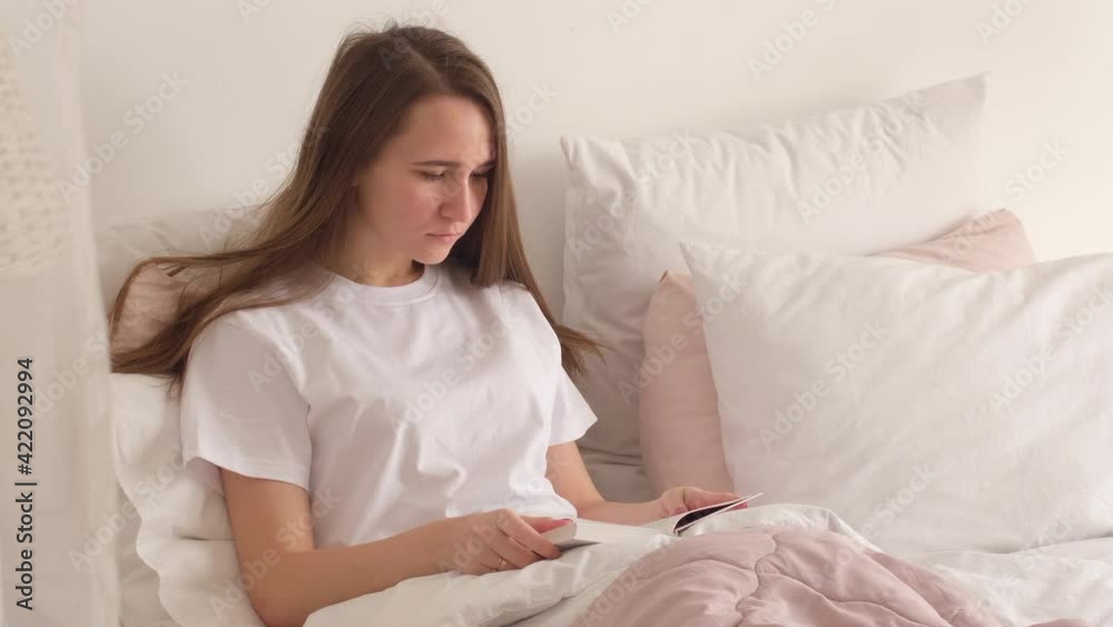 Young woman with long hair lying on bed at home and reading a book. Leisure at home, Stay in the house, Beautiful girl, home weekend. Young woman with long hair lying on bed at home and reading a book. Leisure at home, Stay in the house, Beautiful girl, home weekend.