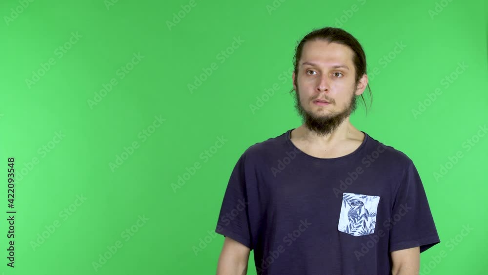 Portrait of a young darkhaired bearded man looking at the camera and flinching sharply from surprise or fear. A man in the studio on a green screen. Close up.