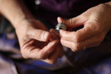 Old woman hands fingers threading a bobbin with lilac thread into the shuttle of an sewing machine