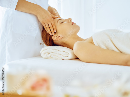Beautiful woman enjoying facial massage with closed eyes in spa center. Relax treatment concept in medicine
