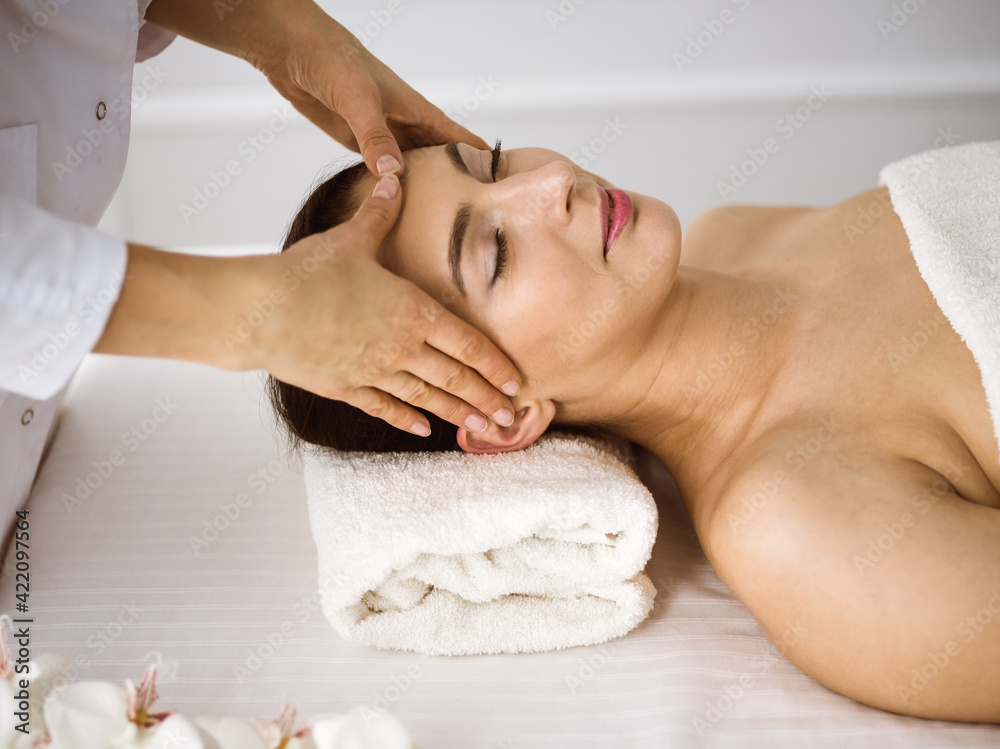 Beautiful brunette woman enjoying facial massage comfortable and bissfulle. Relaxing treatment in medicine and spa center concepts Beautiful brunette woman enjoying facial massage comfortable and bissfulle. Relaxing treatment in medicine and spa center concepts