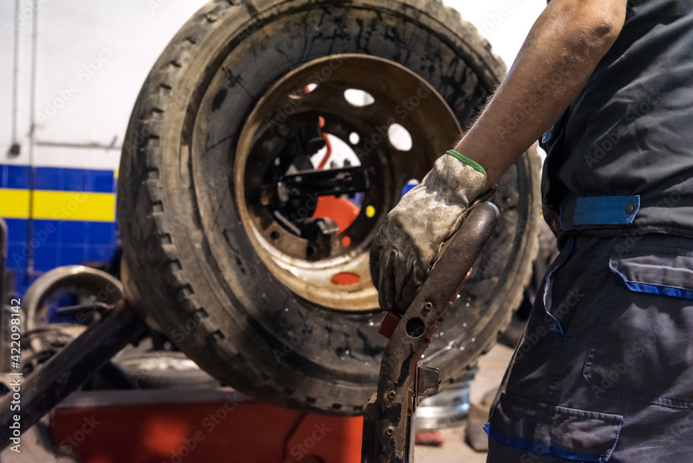 Tire workshop operator who uses a machine to mount or remove a truck wheel. Tire workshop operator who uses a machine to mount or remove a truck wheel.