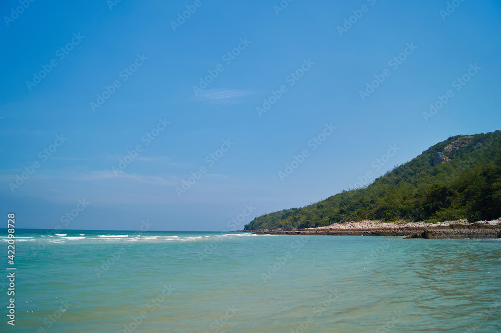 Green island in Thailand near the sea, against the blue sky