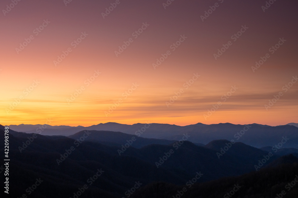 Faint Clouds Hang Over Mountain Ridges At Sunrise