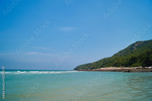 Green island in Thailand near the sea, against the blue sky