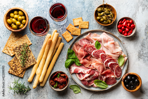 Appetizers with differents antipasti, charcuterie, snacks and red wine. Sausage, ham, tapas, olives and crackers for buffet party. Top view, flat lay