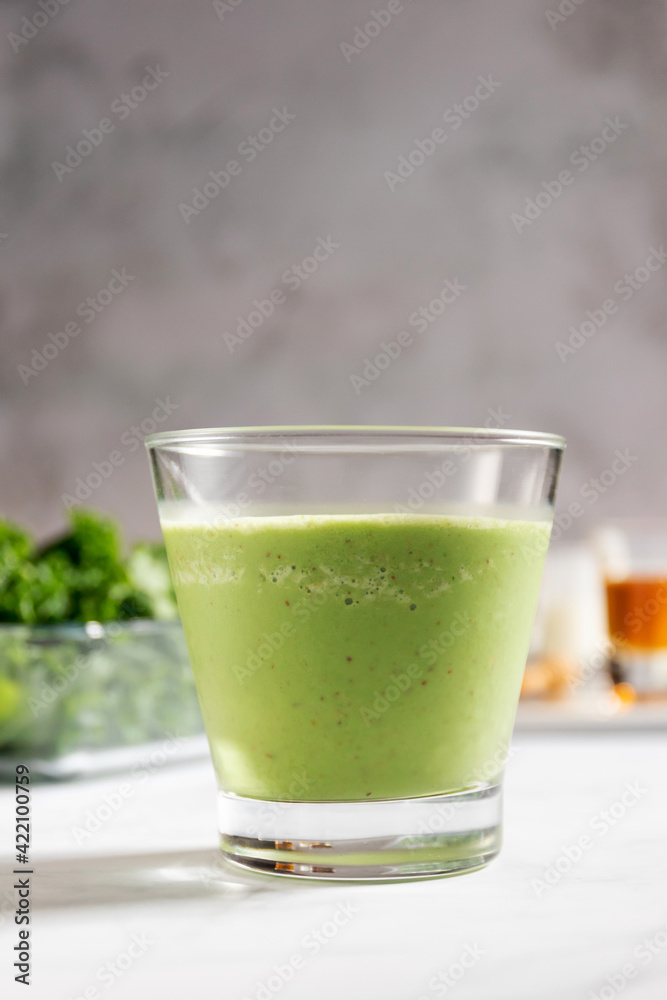Healthy green kale smoothie with greek yogurt, almond and honey in glass isolated on white table background. Kale is considered a superfood because it's a great source of vitamins and minerals. Healthy green kale smoothie with greek yogurt, almond and honey in glass isolated on white table background. Kale is considered a superfood because it's a great source of vitamins and minerals.