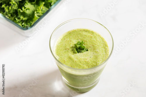 Healthy green kale smoothie with greek yogurt in a glass isolated on white table background, top view. Kale is considered a superfood because it's a great source of vitamins and minerals.