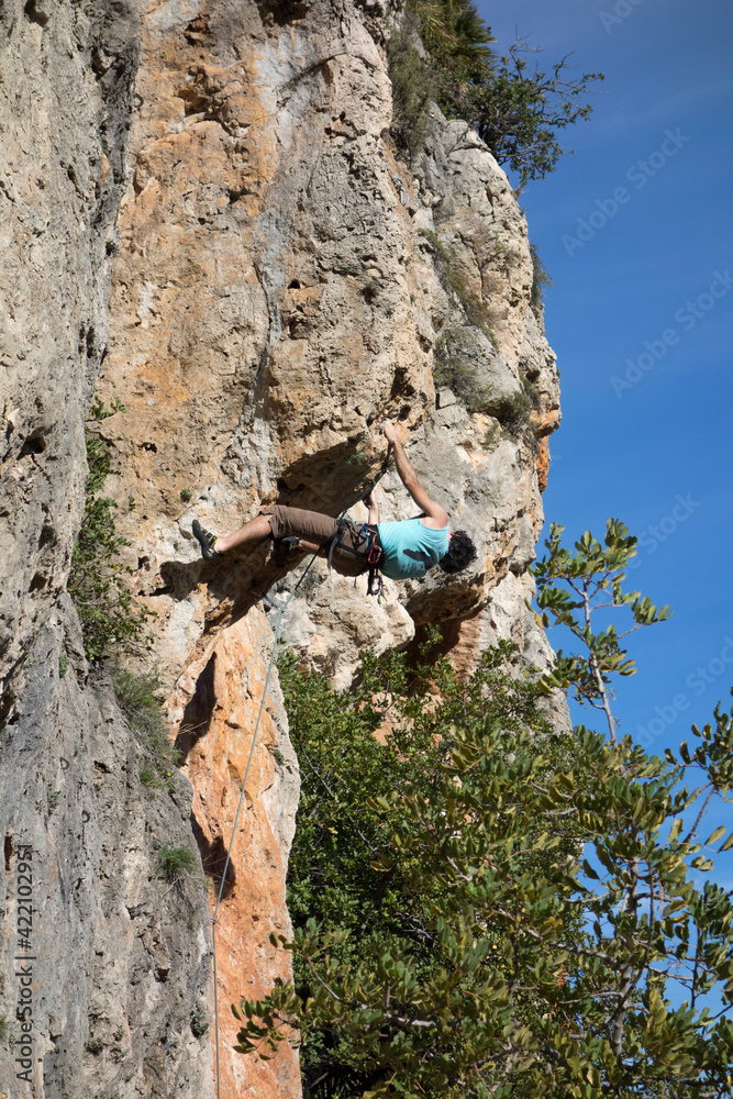 man climbing a mountain with rope