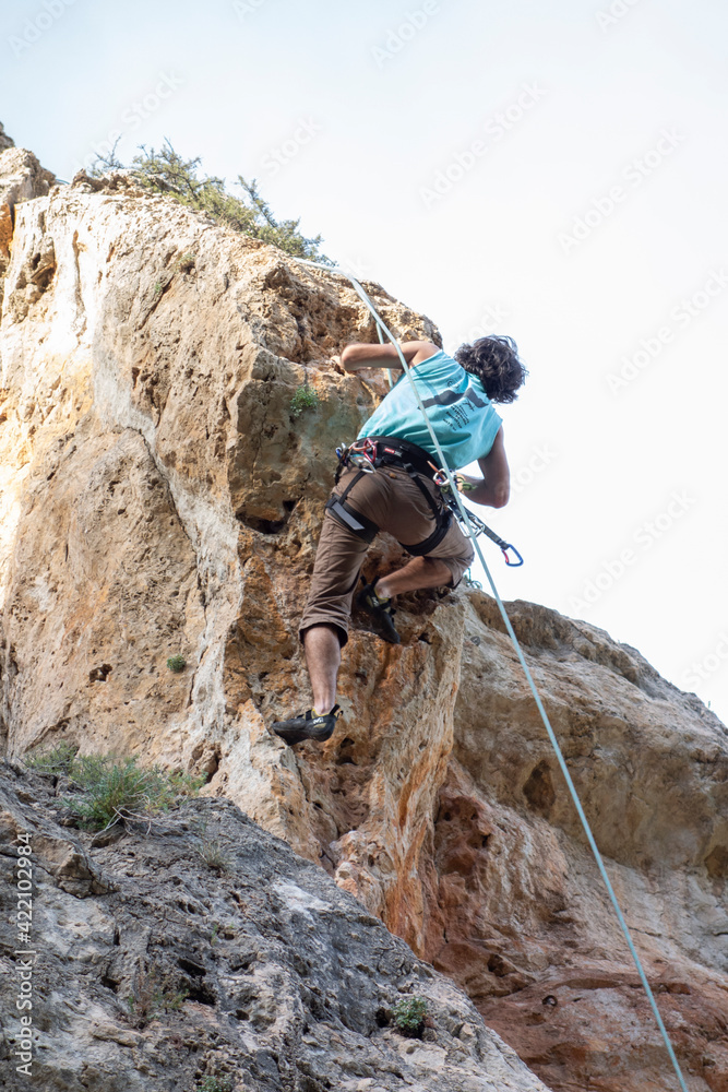 man climbing a mountain with rope