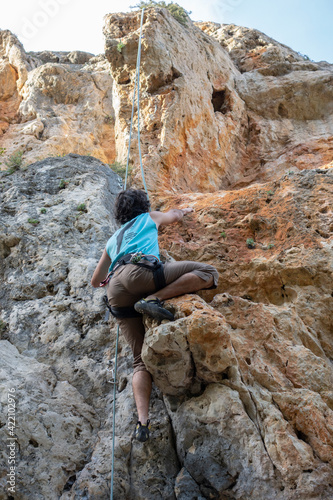 man climbing a mountain with rope