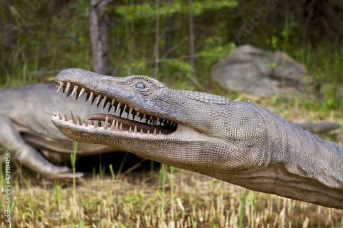 A model of a prehistoric dinosaur made available to visitors to a Jurassic park to learn about the history of many millions of years. In the background, vegetation and terrain resembling the natural h