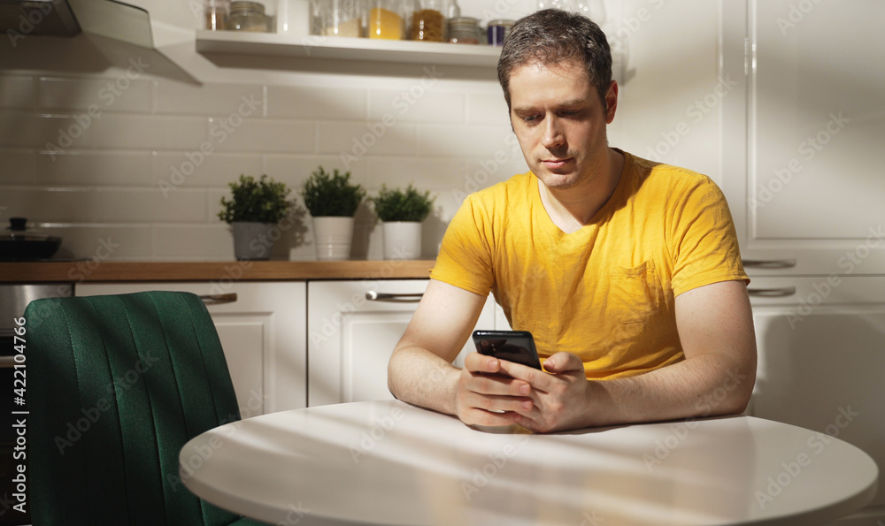 Man using a smartphone in the kitchen. Man using a smartphone in the kitchen.
