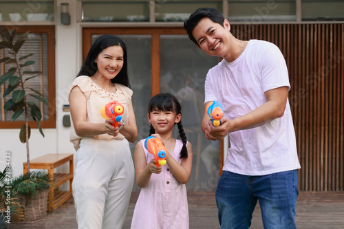 Photography Young adult Asian family having fun playing water gun on play yard, Songkran holiday in Thailand