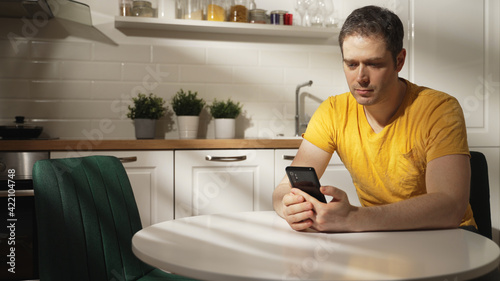 Man using a smartphone in the kitchen.