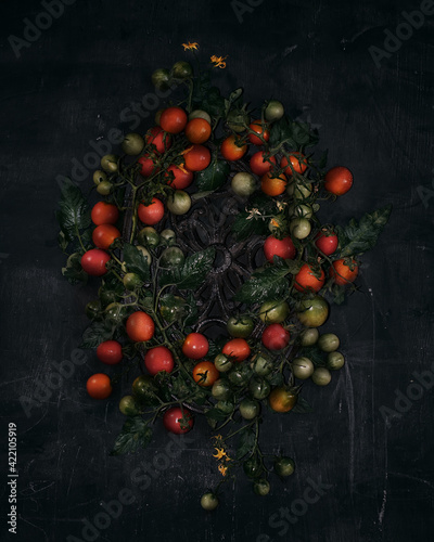 flat lay, cherry tomato wreath top view on textured black background closeup. Selective focus