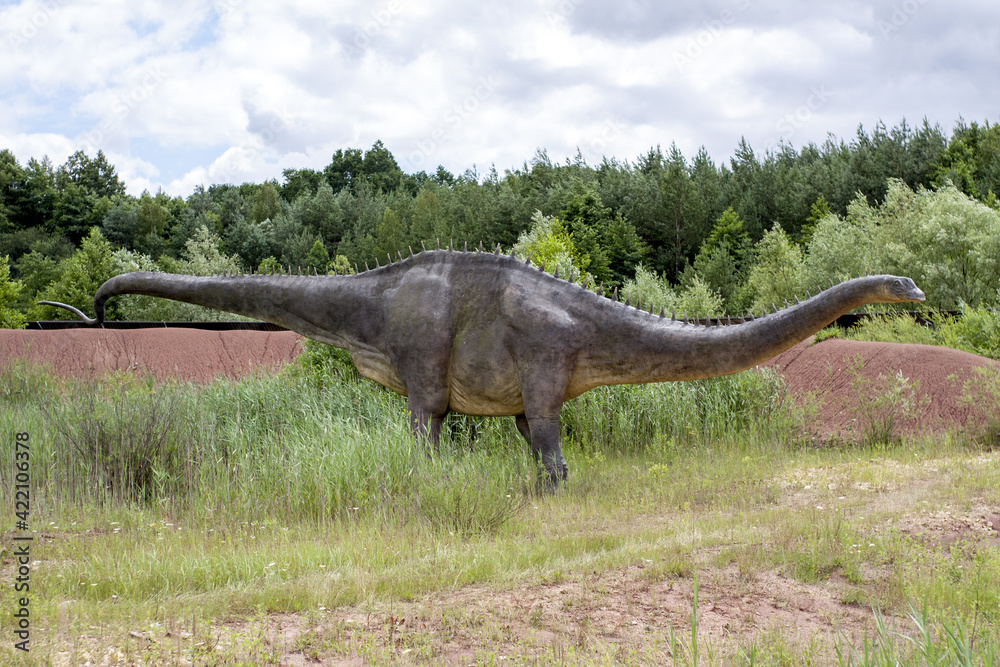 Obraz premium A model of a prehistoric dinosaur made available to visitors to a Jurassic park to learn about the history of many millions of years. In the background, vegetation and terrain resembling the natural h