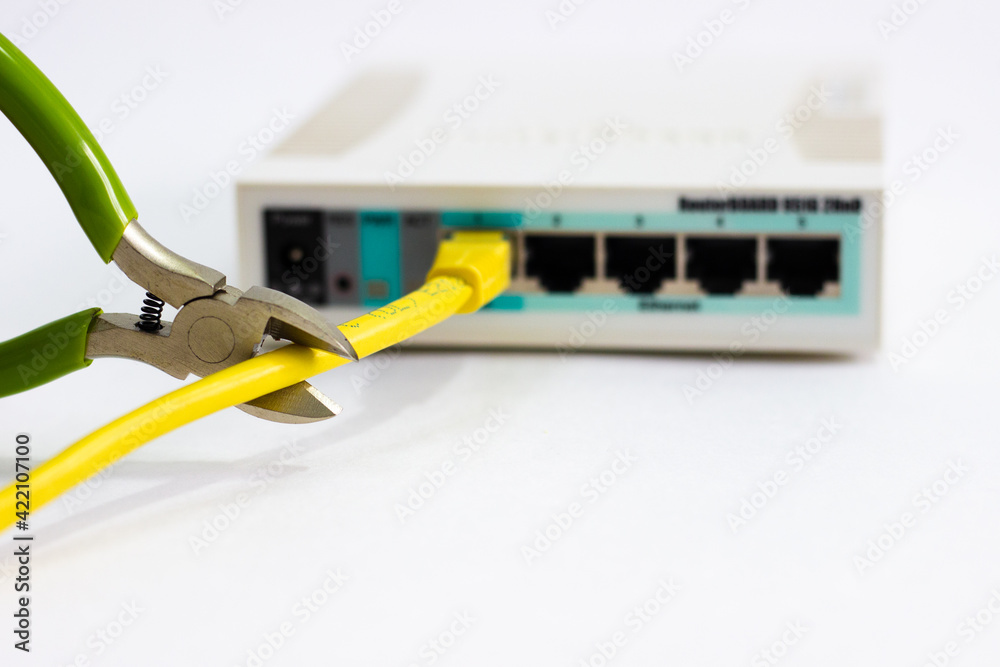Cuts cable on router. Man cuts cord of Wi-Fi router. White router with cut cord. Side cutters cut cable on white background. Network cable in router is damaged. Hand cuts cable. Cuts cable on router. Man cuts cord of Wi-Fi router. White router with cut cord. Side cutters cut cable on white background. Network cable in router is damaged. Hand cuts cable.