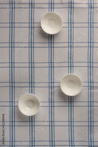 White empty drinking bowls on checkered tablecloth