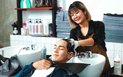 Hairdresser washing hair to her handsome client. Man at barbershop. Hairstylist washing hair to handsome young man in beauty salon. 
