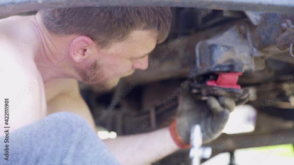guy repairs an old car, changes shock absorbers, close-up, guy lies under a truck guy repairs an old car, changes shock absorbers, close-up, guy lies under a truck