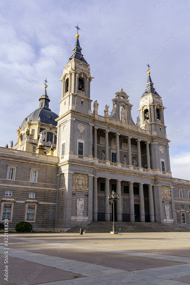Main facade of the Almudena cathedral in Madrid on sunny day with clouds.