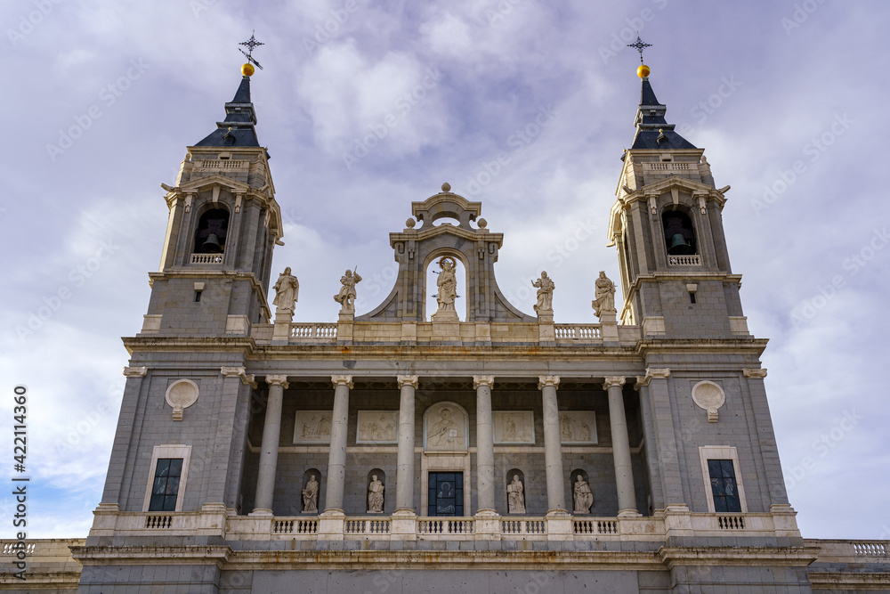 Main facade of the Almudena cathedral in Madrid on sunny day with clouds.