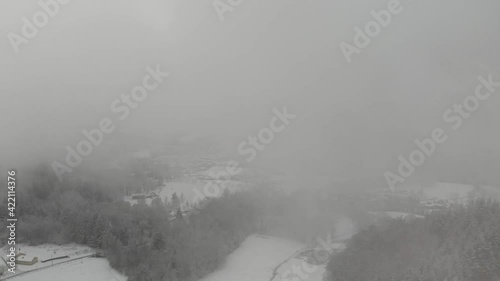 Aerial shot by drone of countryside in snowy winter, very thick fog. Auvergne, France