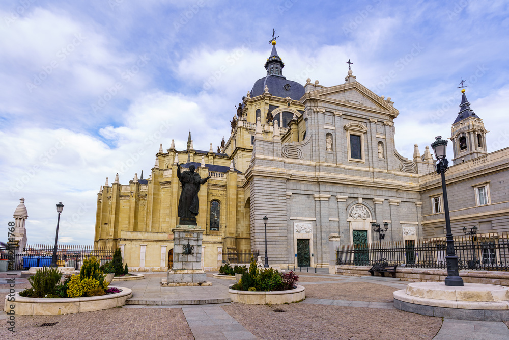 Main entrance of the Almudena cathedral in Madrid, blue sky with clouds.
