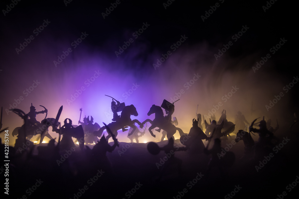 Medieval battle scene with cavalry and infantry. Silhouettes of figures as separate objects, fight between warriors on sunset foggy background. Medieval battle scene with cavalry and infantry. Silhouettes of figures as separate objects, fight between warriors on sunset foggy background.