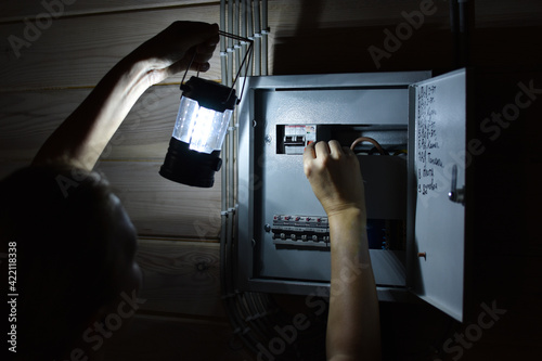 Power outage in house. Extra light went out in room. A person with a lantern checks electrical panel.