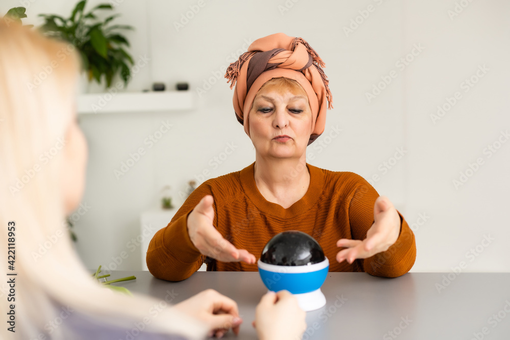 Female Fortuneteller or esoteric Oracle, sees in the future by looking into their crystal ball during a Seance to interpret them and to answer questions Female Fortuneteller or esoteric Oracle, sees in the future by looking into their crystal ball during a Seance to interpret them and to answer questions